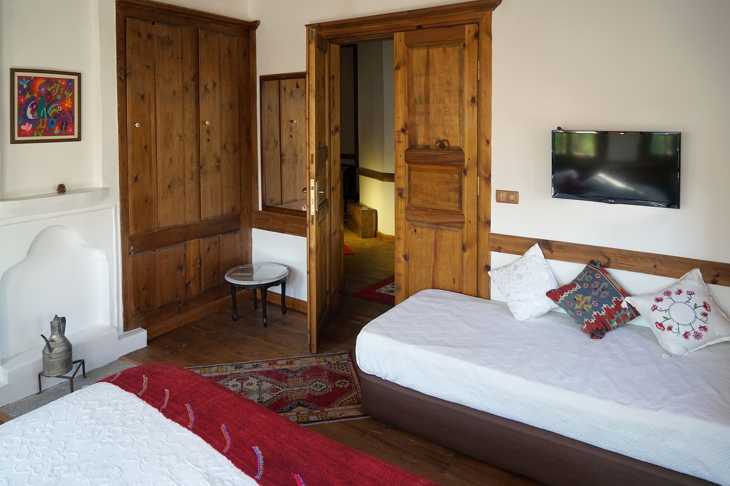 Un dormitori amb un llit, televisió, portes de fusta i una taula petita.