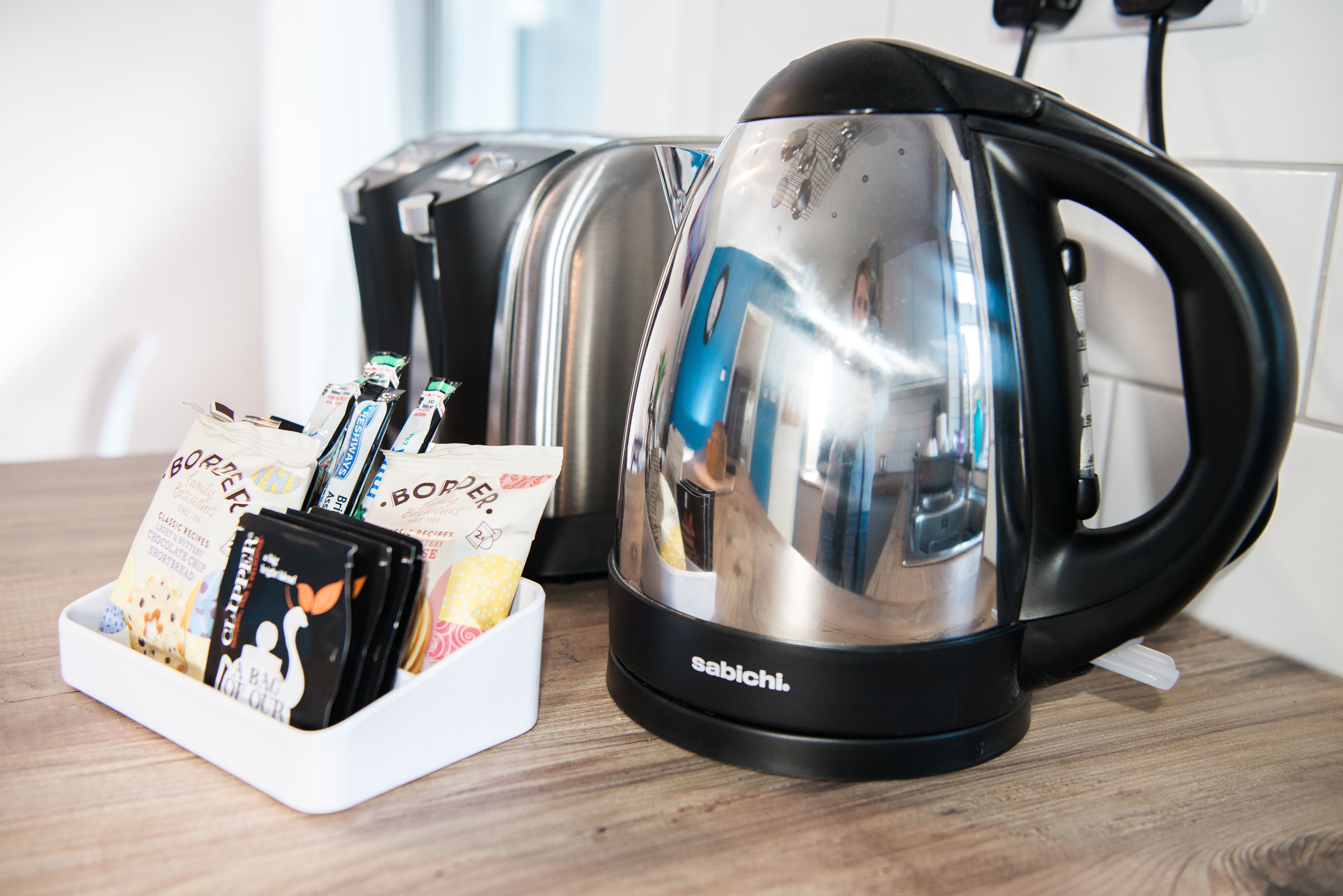 A kitchen with two stainless steel kettles and a white tray holding chocolate bars.