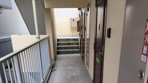 Um corredor estreito com grades de metal, piso de concreto e portas em um lado.