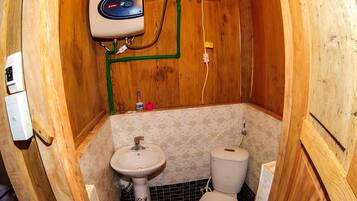 A small, wooden bathroom with a toilet, sink, and a water heater.