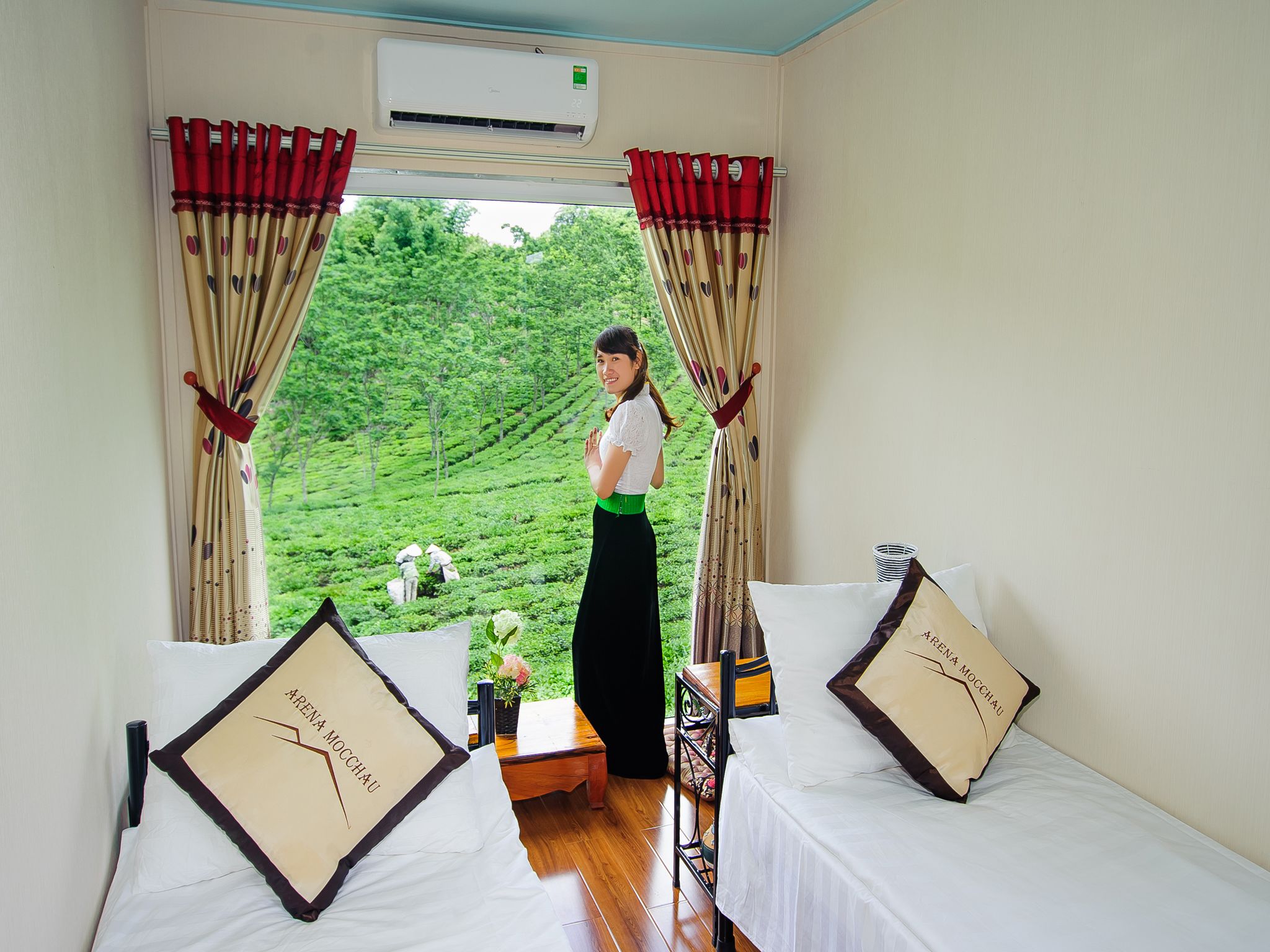 Una habitación con una cama, una mesita con un florero y una ventana con cortinas.