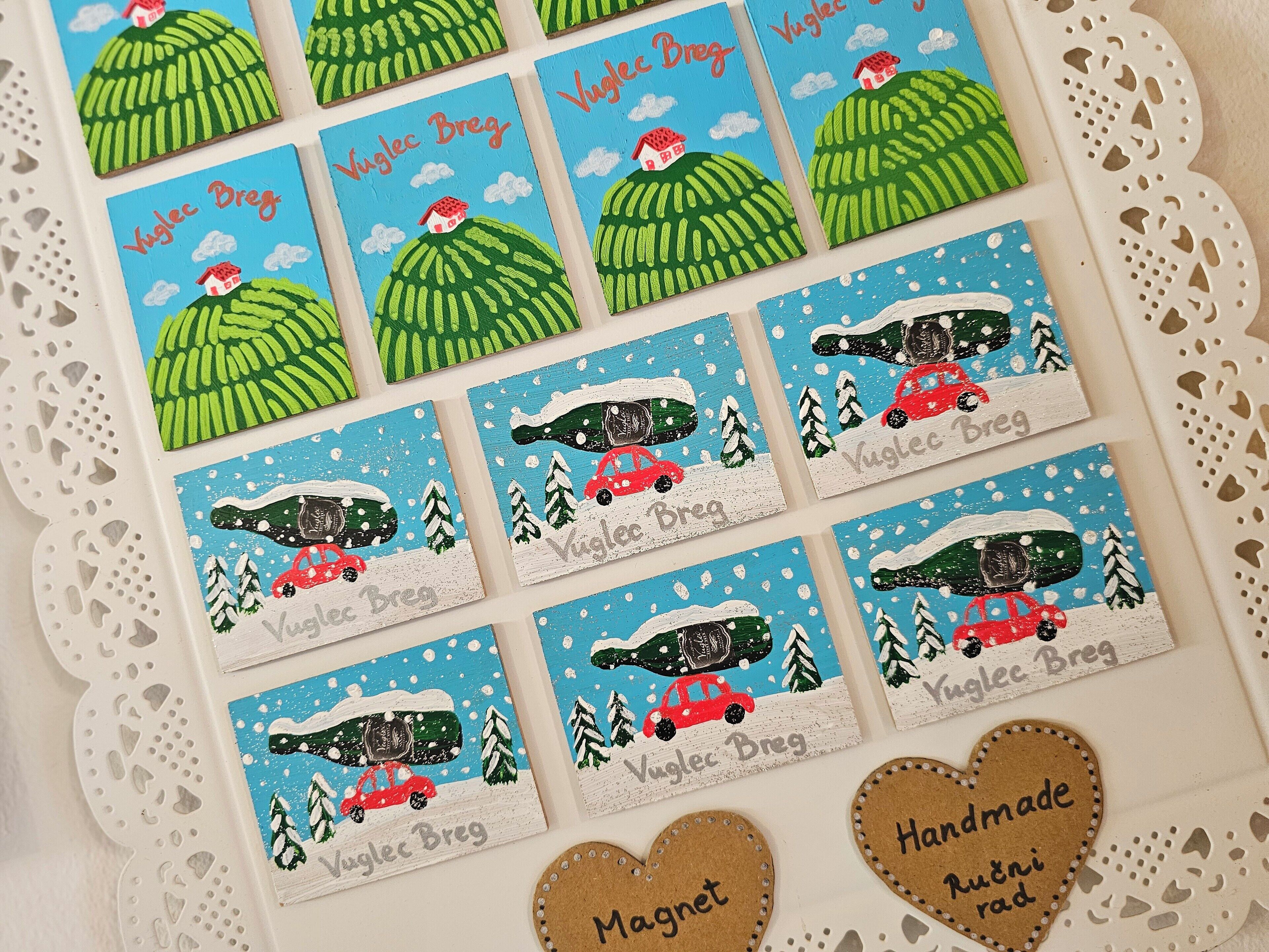 A collection of name tags with a green hill and a red house design, and two heart-shaped magnets with text.