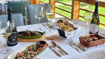 Una mesa de comedor dispuesta con varios platos, copas de vino y botellas.