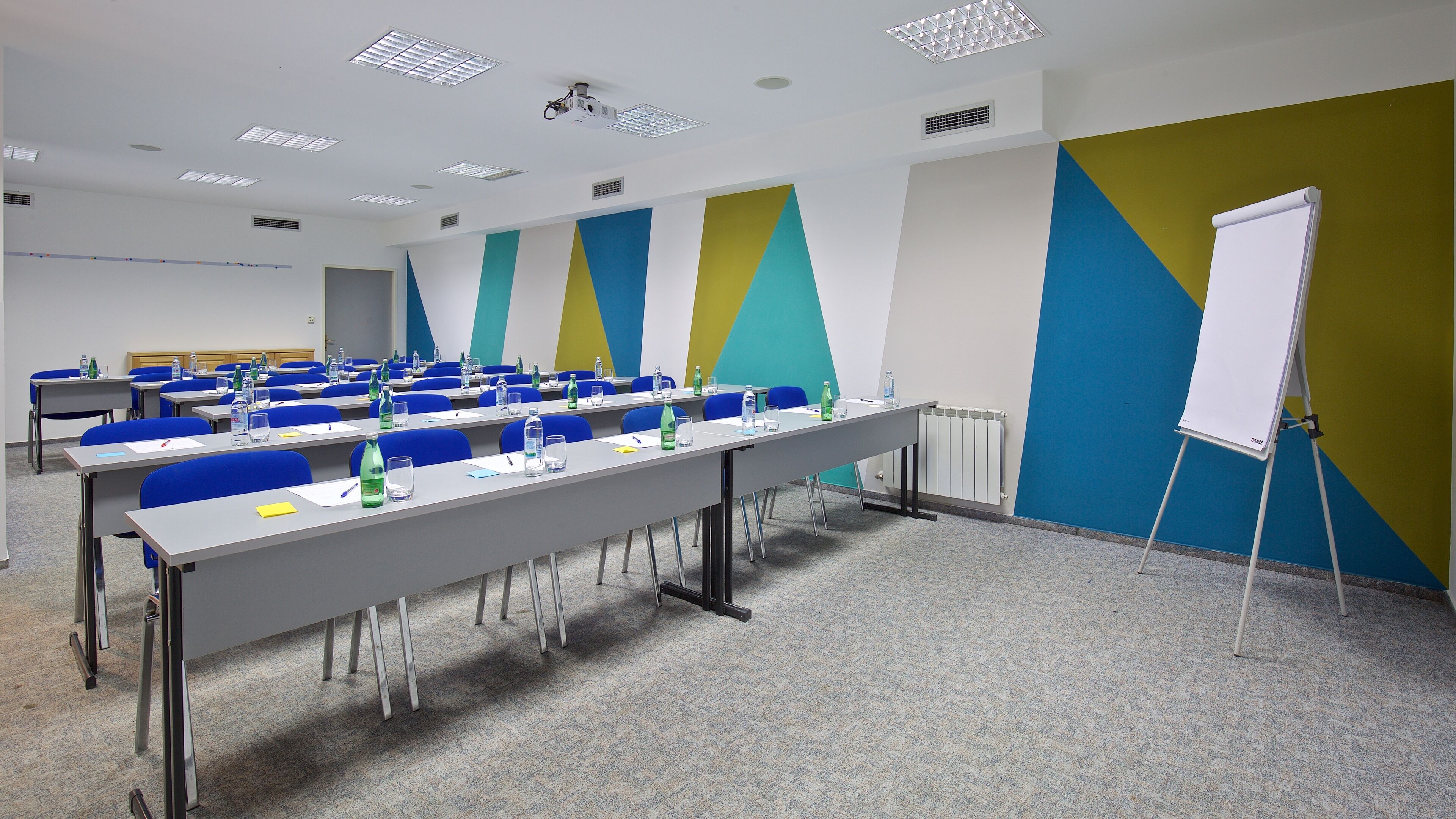 A conference room with tables, chairs, and a whiteboard.