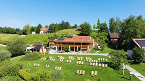 A large building with multiple solar panels on the roof, surrounded by a grassy area with numerous lounge chairs. - Vuglec Breg (Krapina)