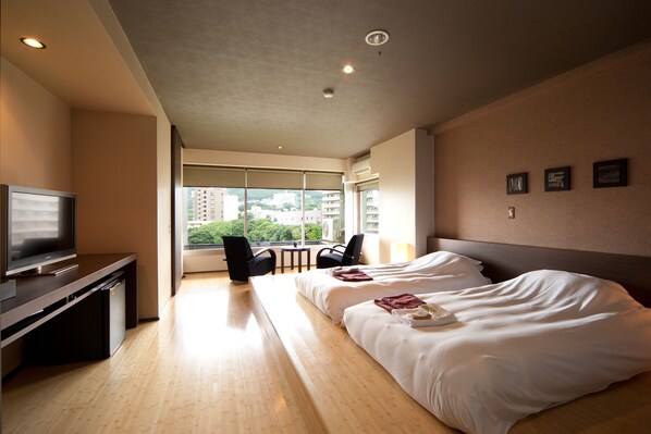 A hotel room with a bed, a TV, a desk, and a view of the city. - Ito Yuki Tei (Ito)
