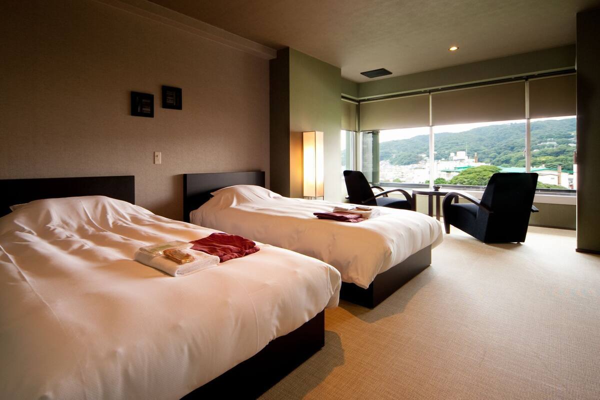 A hotel room with two beds, a desk, and a chair.