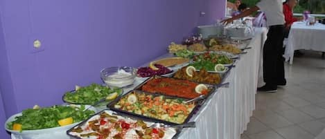 A buffet table with various dishes and a person serving food.