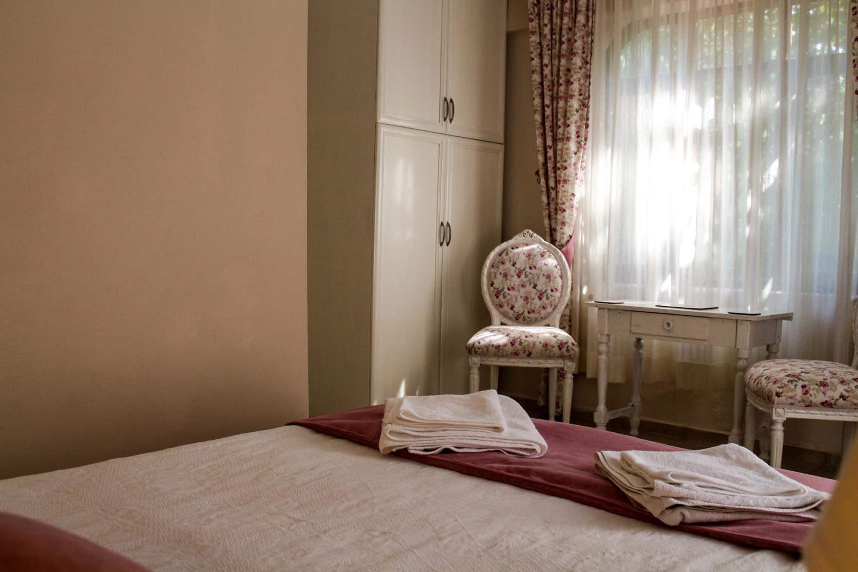 A bedroom with a bed, a chair, a desk, and a wardrobe.