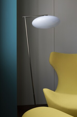 Una silla amarilla y una lámpara de pie en una habitación con una pared color turquesa y un armario gris.