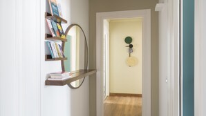 A hallway with a wooden floor, a white door, and a wall-mounted shelf with books. - Castello Sforzesco Suites by Brera Apartments (Milan)