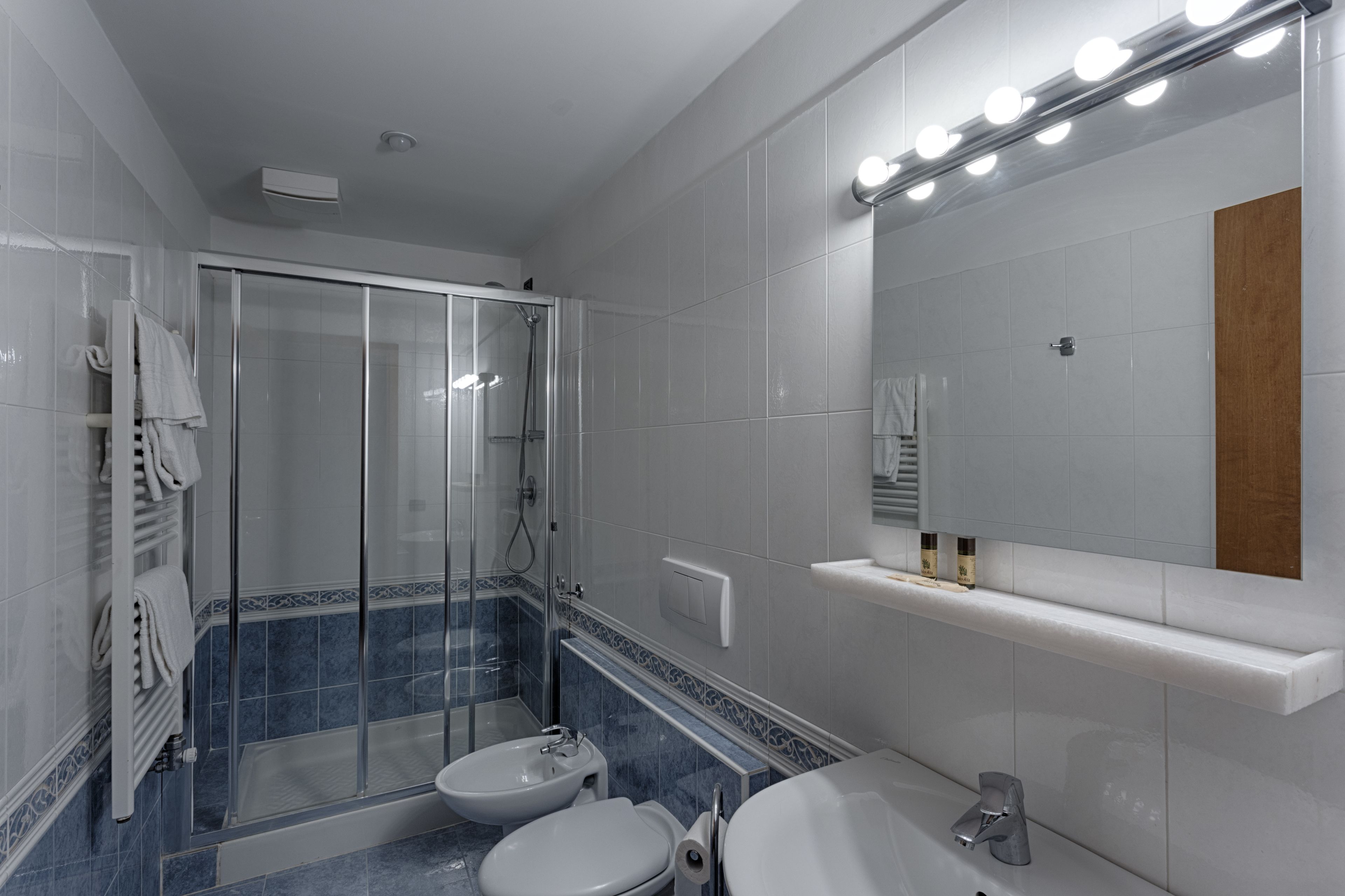 Un baño moderno con ducha envuelta en vidrio, un lavabo, un inodoro y un tocador con espejo.