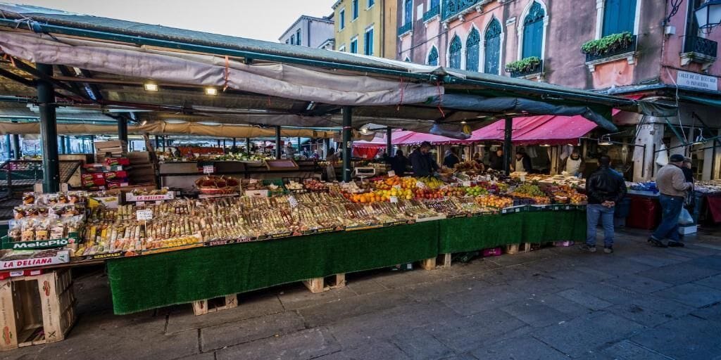 An outdoor market with various stalls selling fresh produce and packaged goods.