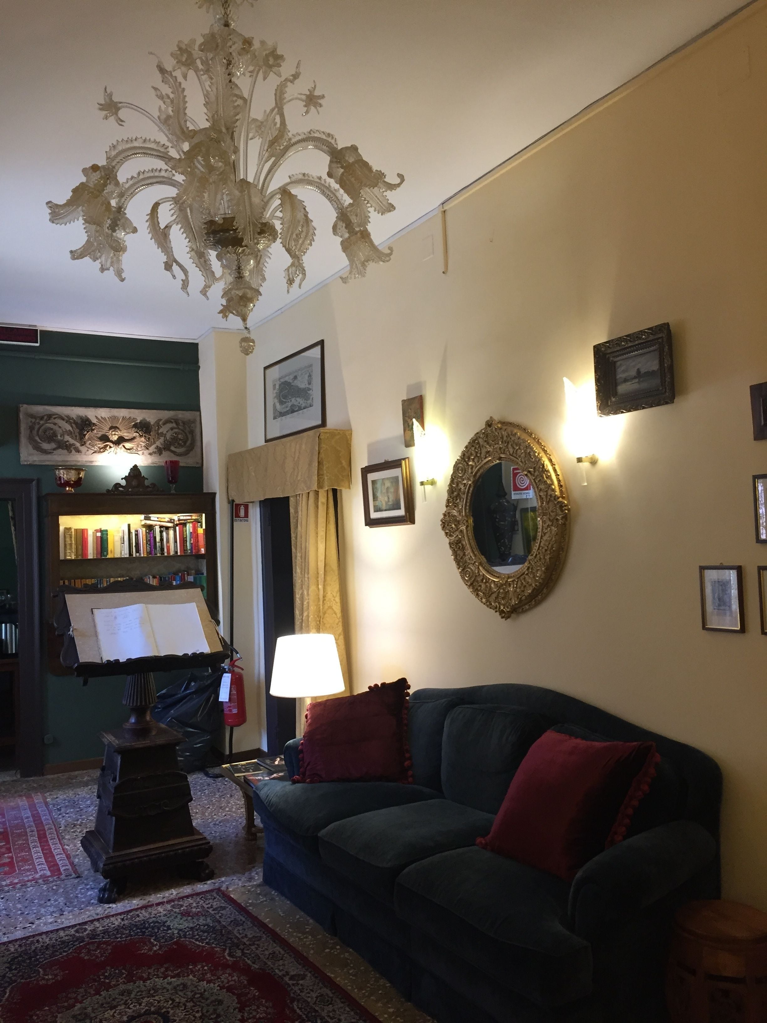Uma sala de estar acolhedora com um sofá verde escuro, um candelabro, uma estante de livros e uma lareira.