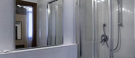 A bathroom with a white sink, a large mirror with lights, and a glass shower enclosure.
