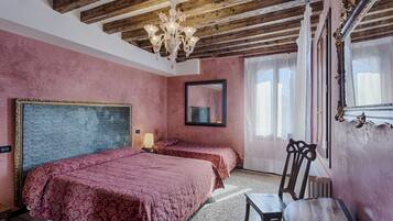 Une chambre avec deux lits, un lustre, un miroir et une fenêtre avec des rideaux.