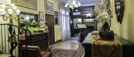 A grand hallway with a chandelier, a staircase, and a large mirror.