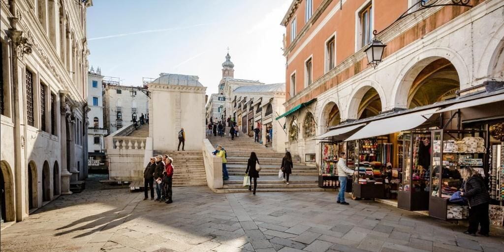 A historic street with stone buildings, a staircase, and shops.