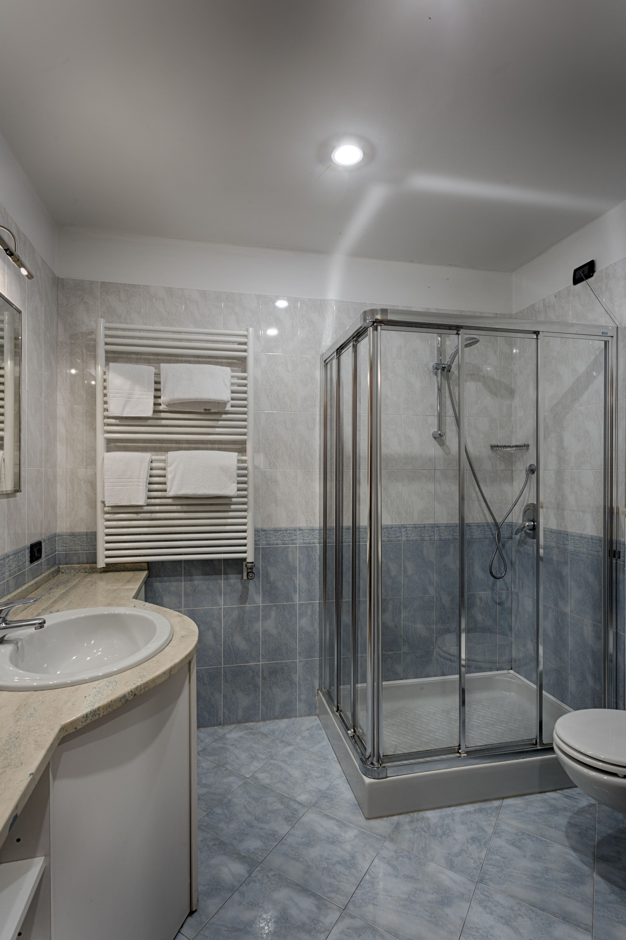 A modern bathroom with a glass-enclosed shower, a sink, and a toilet.