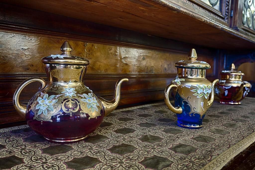 Un ensemble de théières décorées, ornées de motifs floraux, posées sur une nappe à motifs.