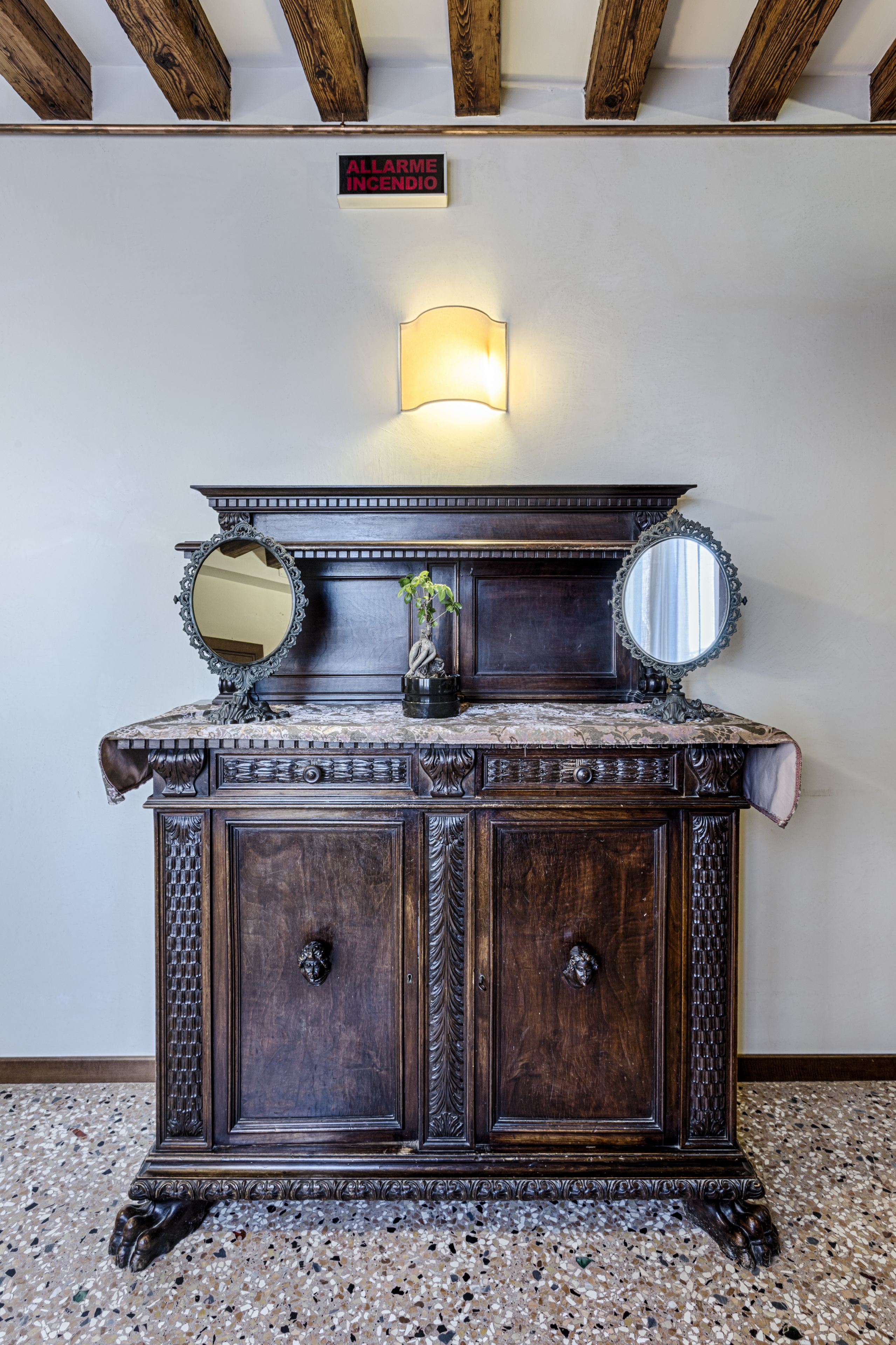 A dark wooden cabinet with two doors, a mirror, and a wall-mounted light fixture.