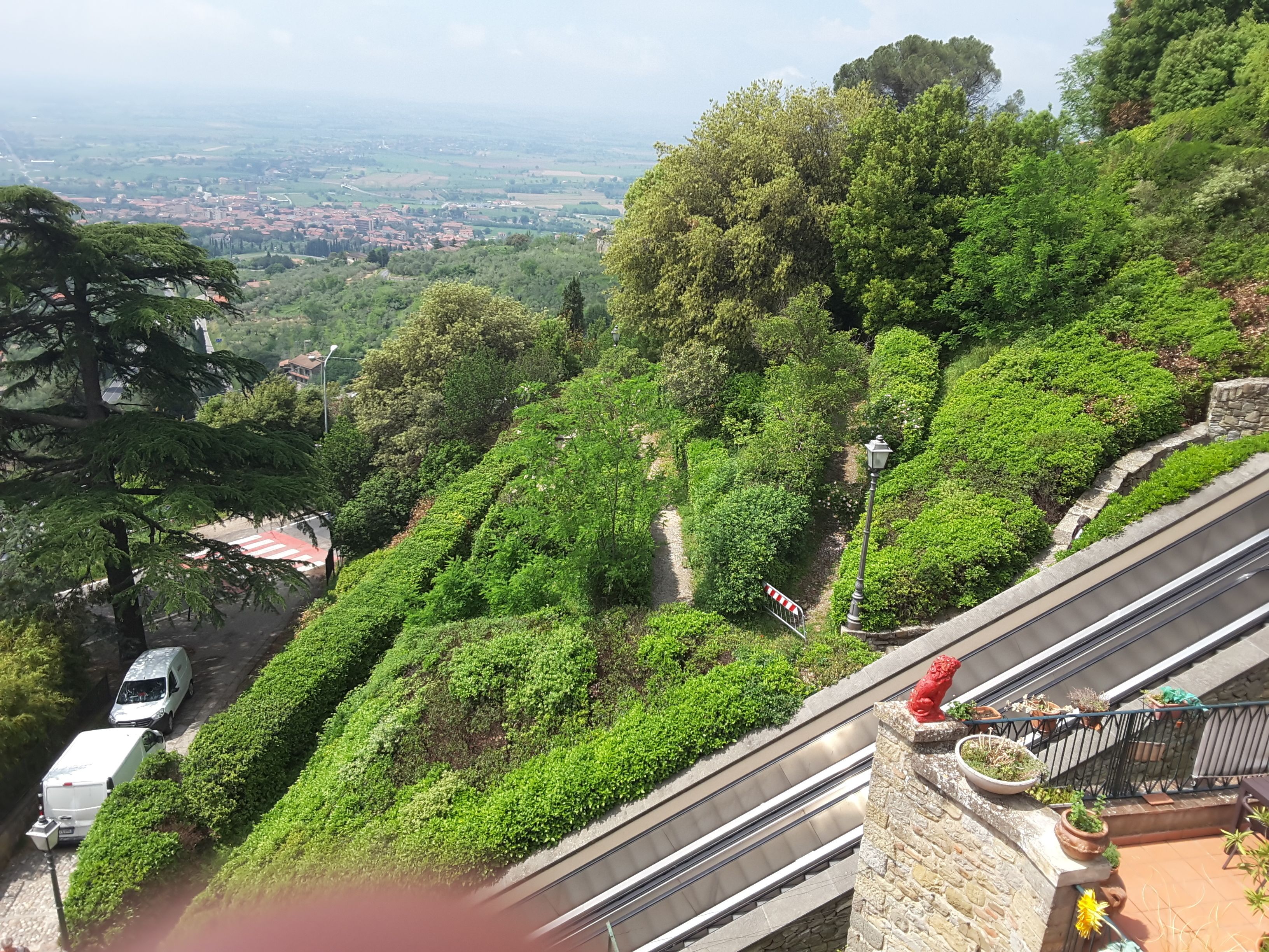 A hillside with a road, a white van, and a red vehicle parked on the side.