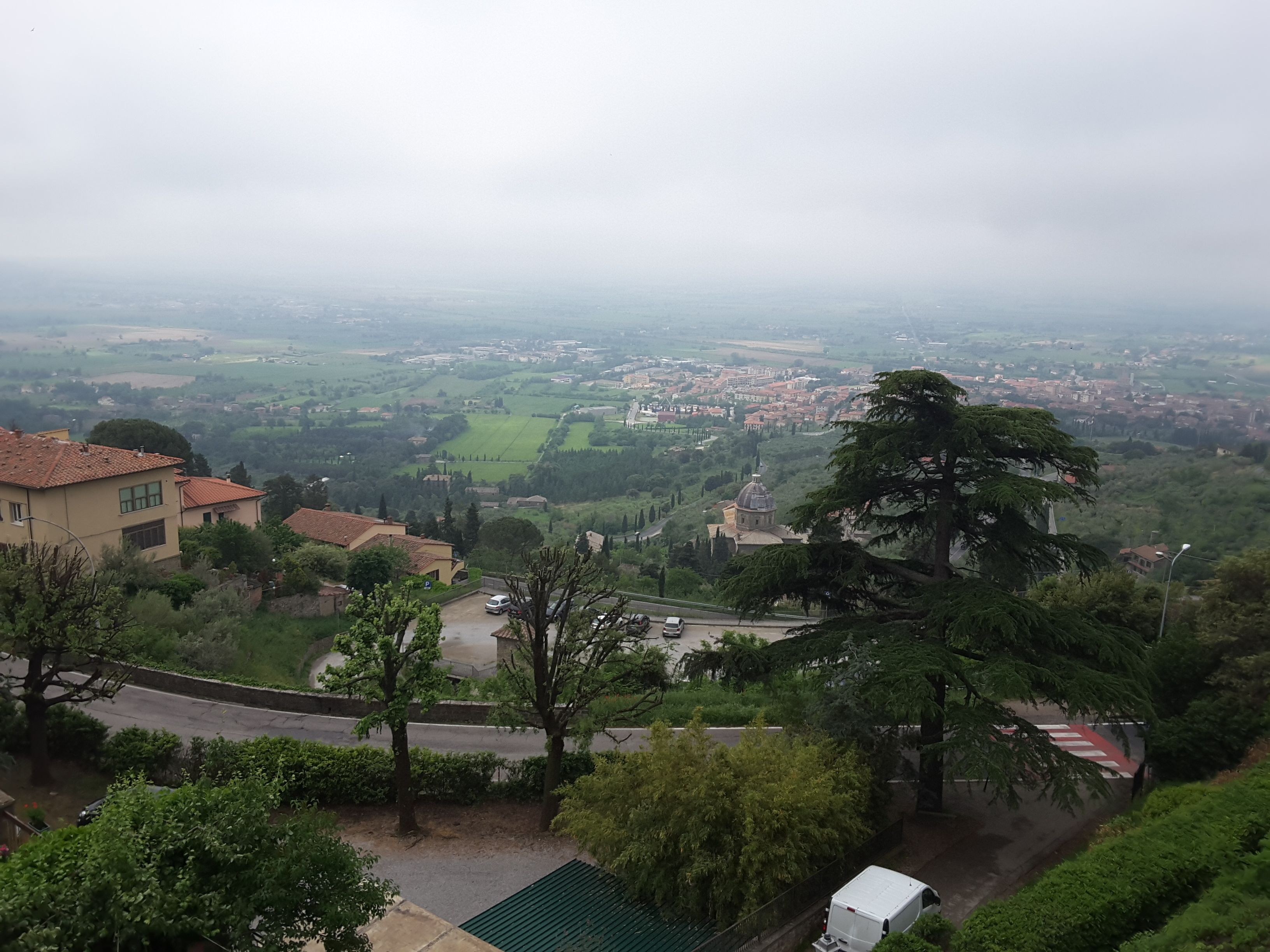 A hillside residential area with a view of a town below.