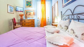 A bedroom with a bed, a dresser, a chair, and a TV.