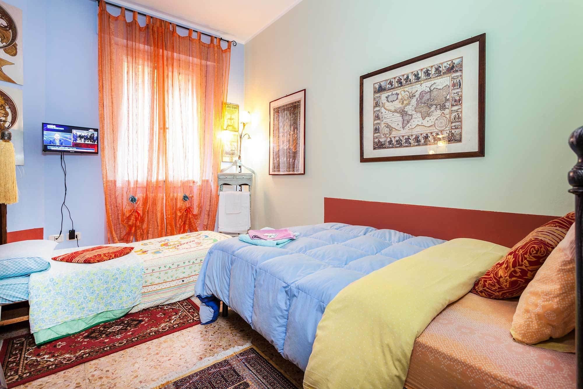 A room with two beds, a television, a lamp, and a framed map on the wall.