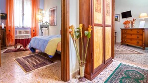 A hotel room with a bed, a dresser, a desk, and a window with curtains. - Casa Kita (Cortona)