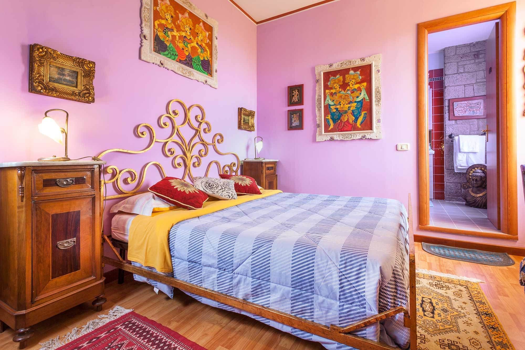 A bedroom with a bed, wooden nightstands, a dresser, and a mirror.