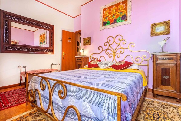 Un dormitorio con una cama, un armario de madera, un espejo y una puerta.