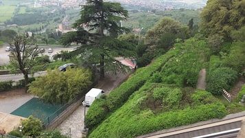 A hillside with a view of a town, a large tree, and a white van parked on the road.
