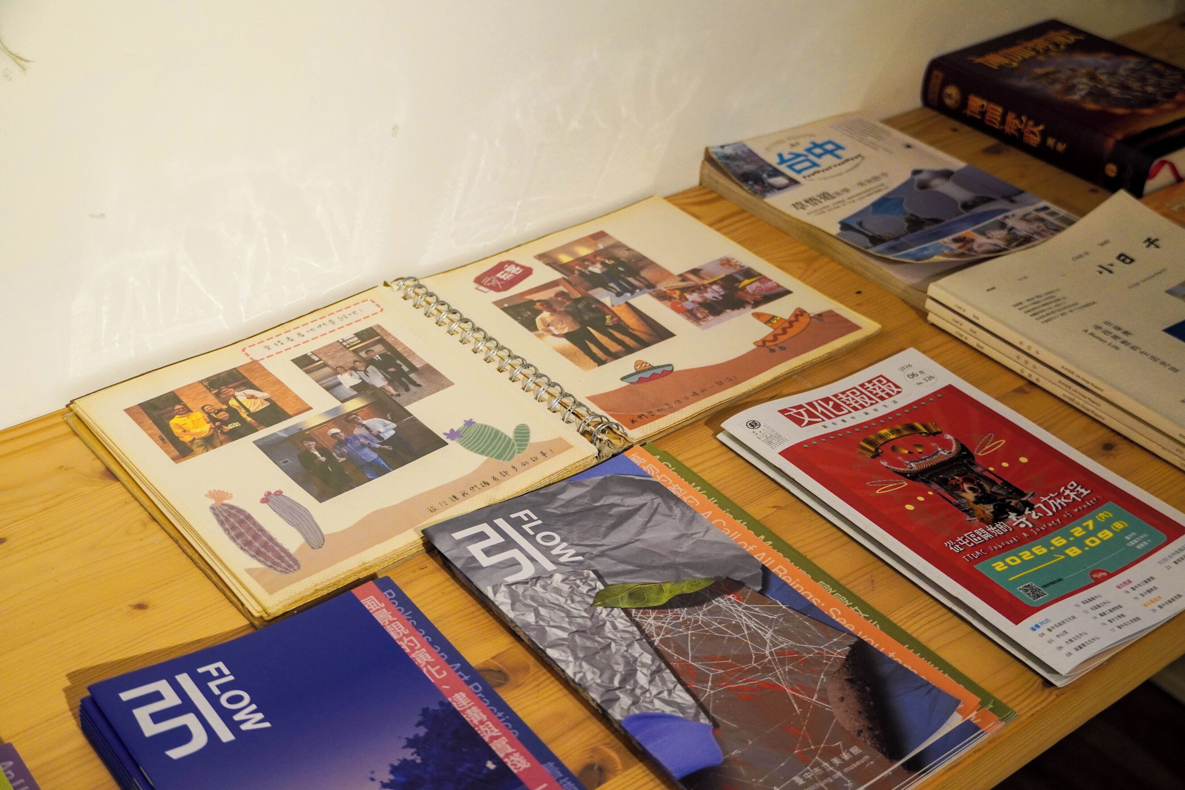 Uma mesa com diversos livros e revistas, incluindo um livro intitulado 'Flow' e uma revista com capa vermelha.