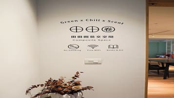 Una pared con un cartel que indica 'Green x Chill x Scent' e iconos para 'No Fumar', 'WiFi Gratis' y 'Libros y Arte'.