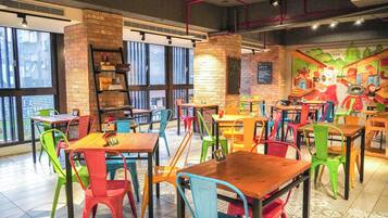 A restaurant interior with colorful chairs and tables, a brick wall, and a mural on the wall.