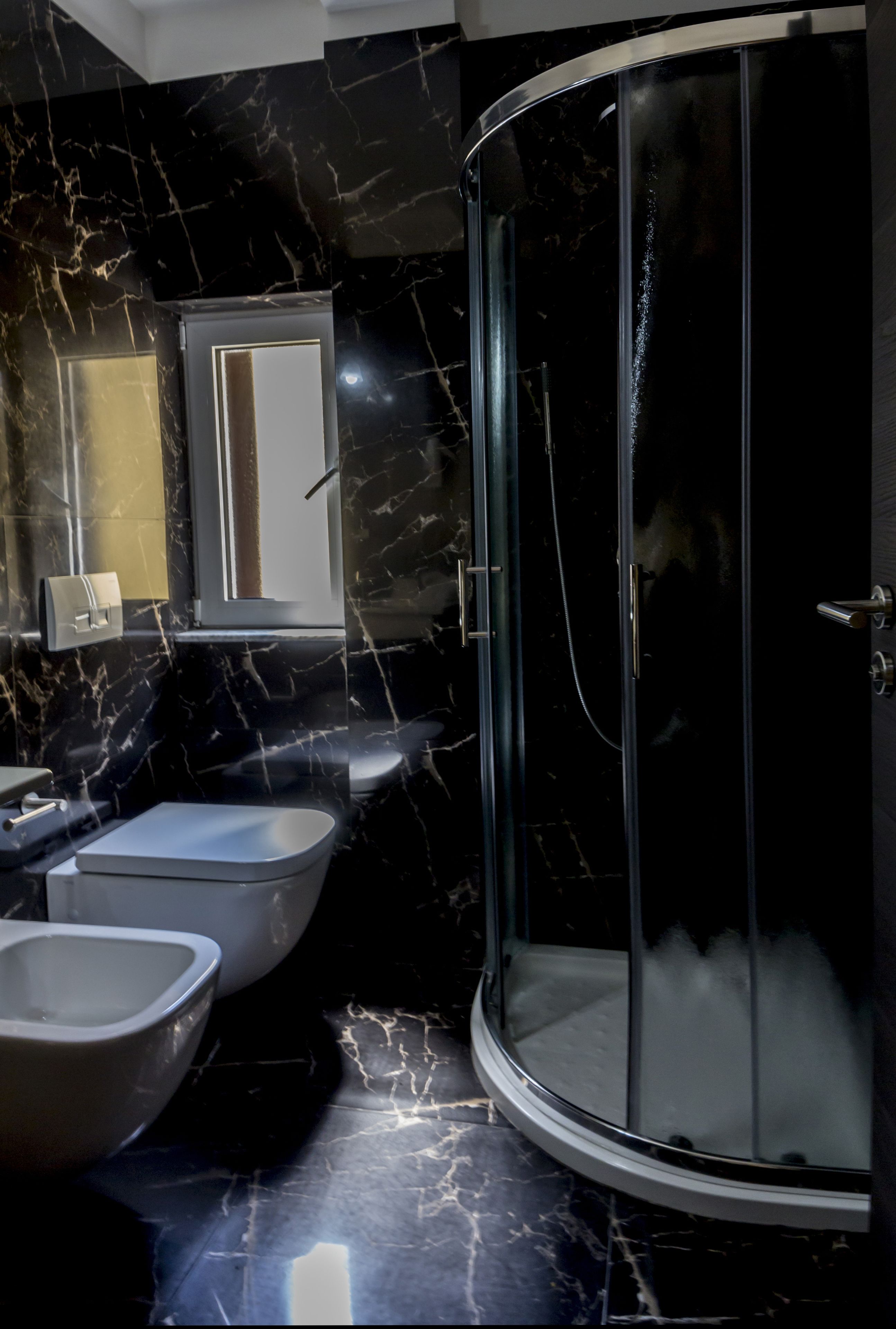 Un baño moderno con mampara de vidrio curva, inodoro y bidé.