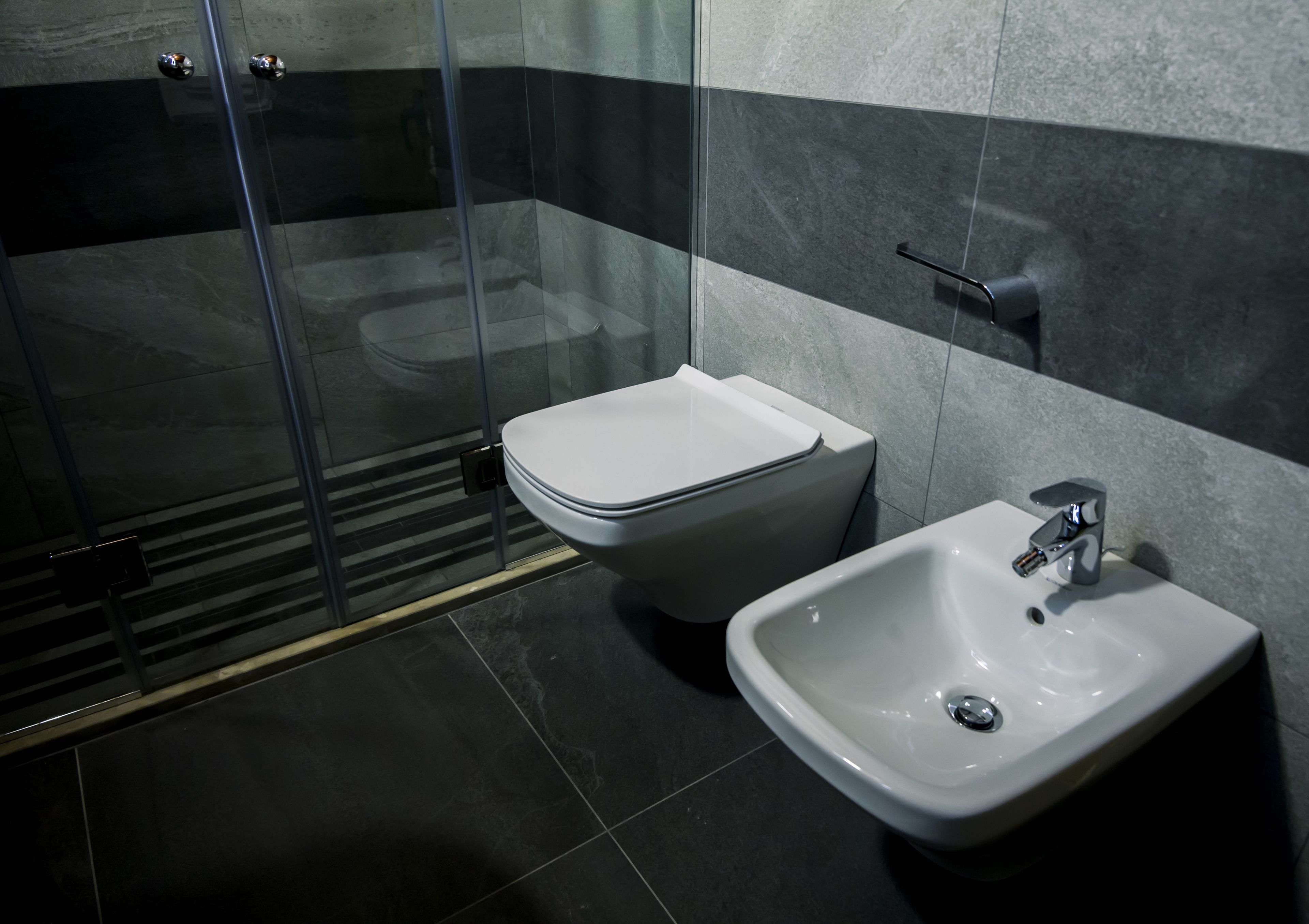 Een moderne badkamer met een douchecabine van glas, een toilet en een wastafel.