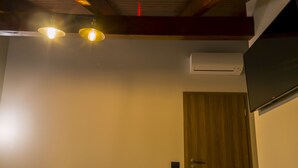 A hotel room with two beds, wooden flooring, a ceiling with exposed beams, and an air conditioning unit. - Hotel Pandora Residence (Tirana)