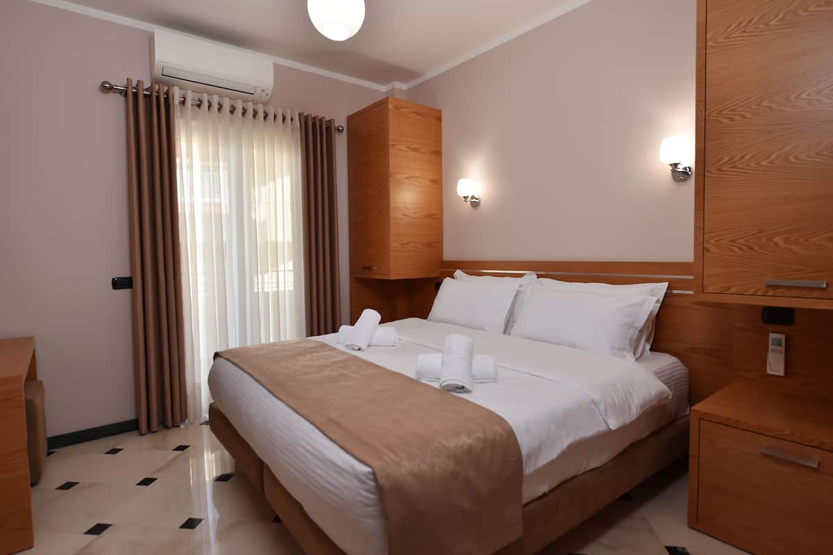 Una habitación de hotel con una cama, un armario de madera y una mesita de noche.
