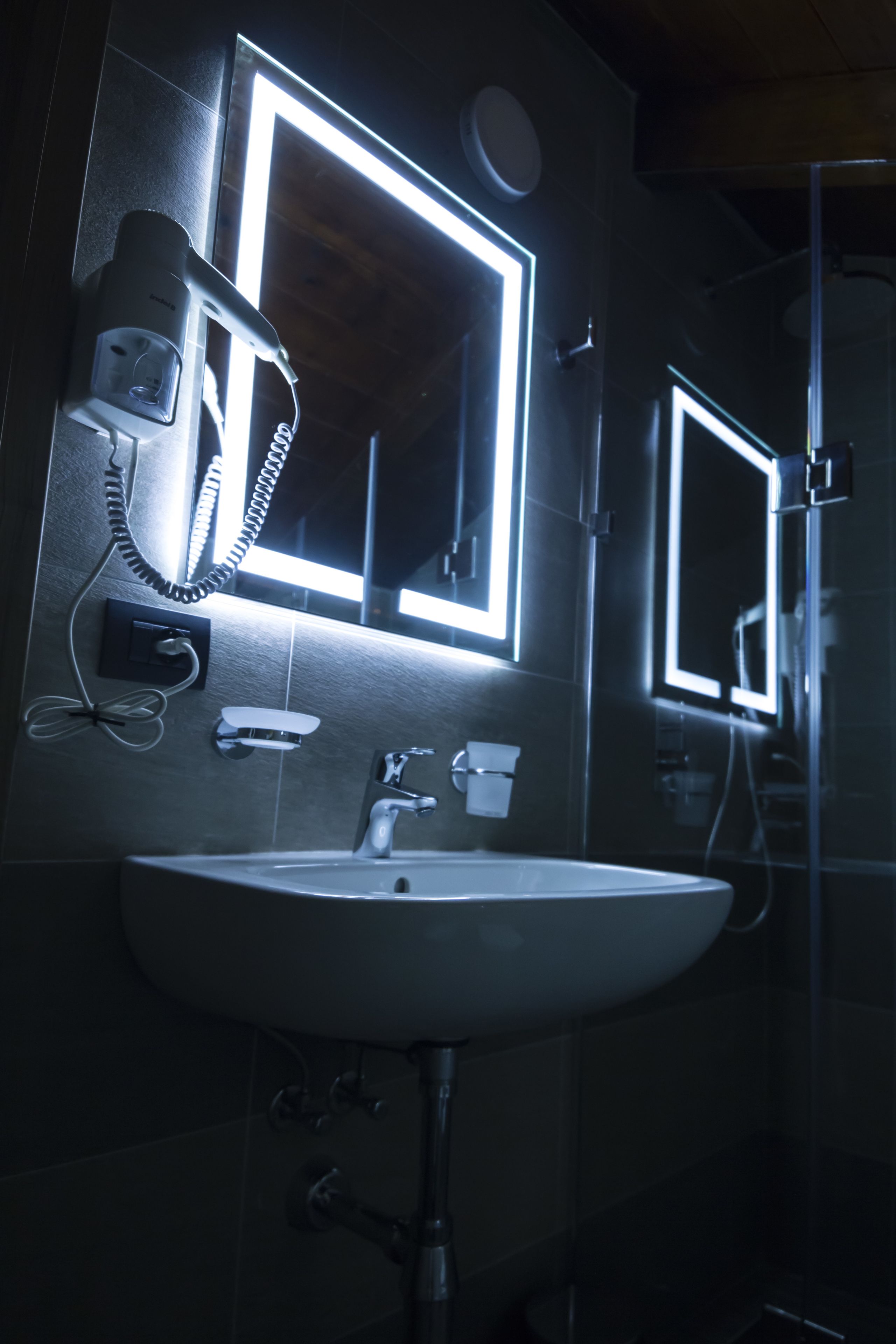 Un baño con lavabo, espejo y secador de pelo.