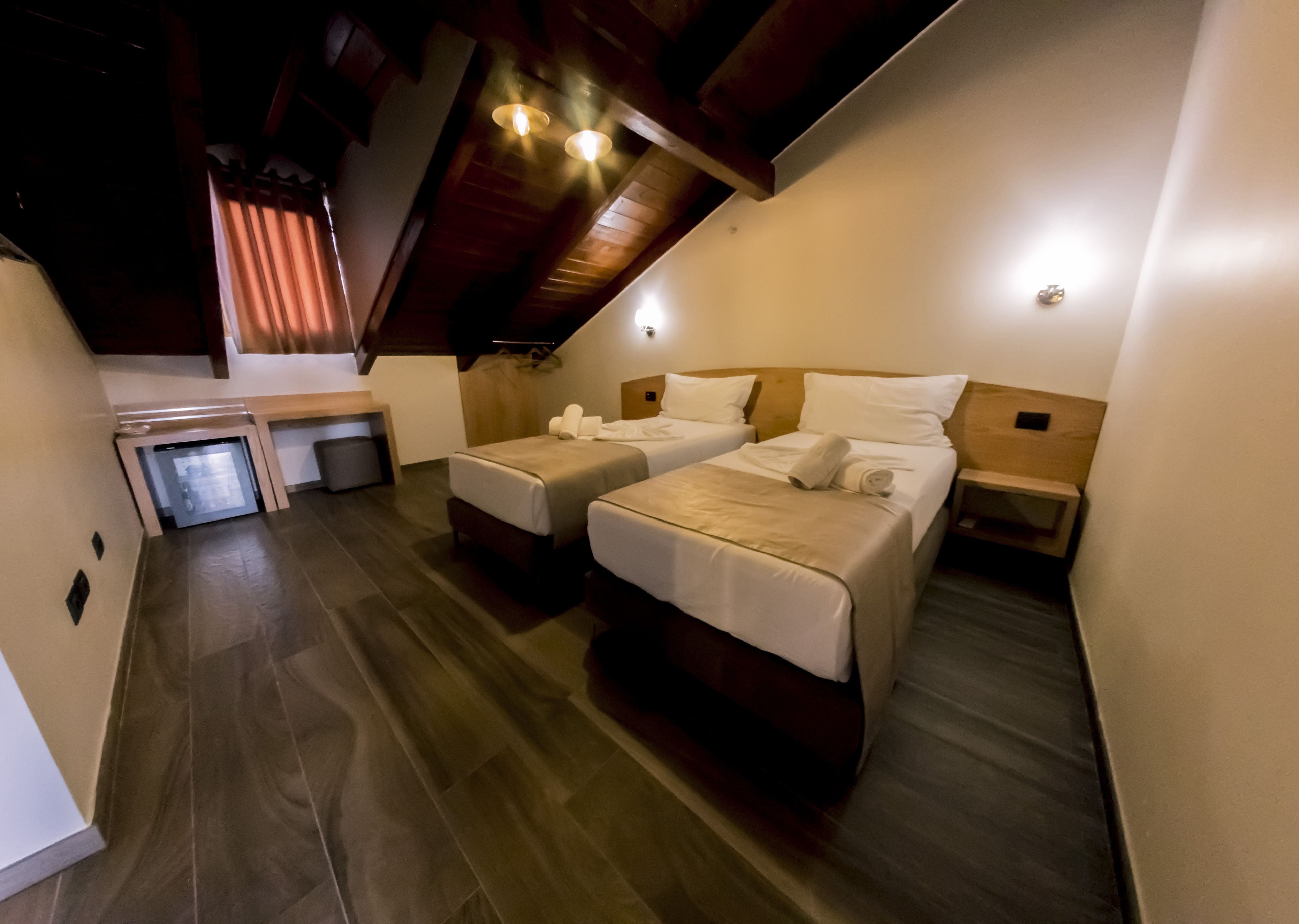Una habitación de hotel moderna con dos camas, un escritorio pequeño y una caja fuerte empotrada.