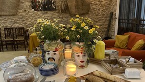 A round table with a white tablecloth, decorated with flowers, a cake, and various food items. - Fattoria Manostalla (Partinico)