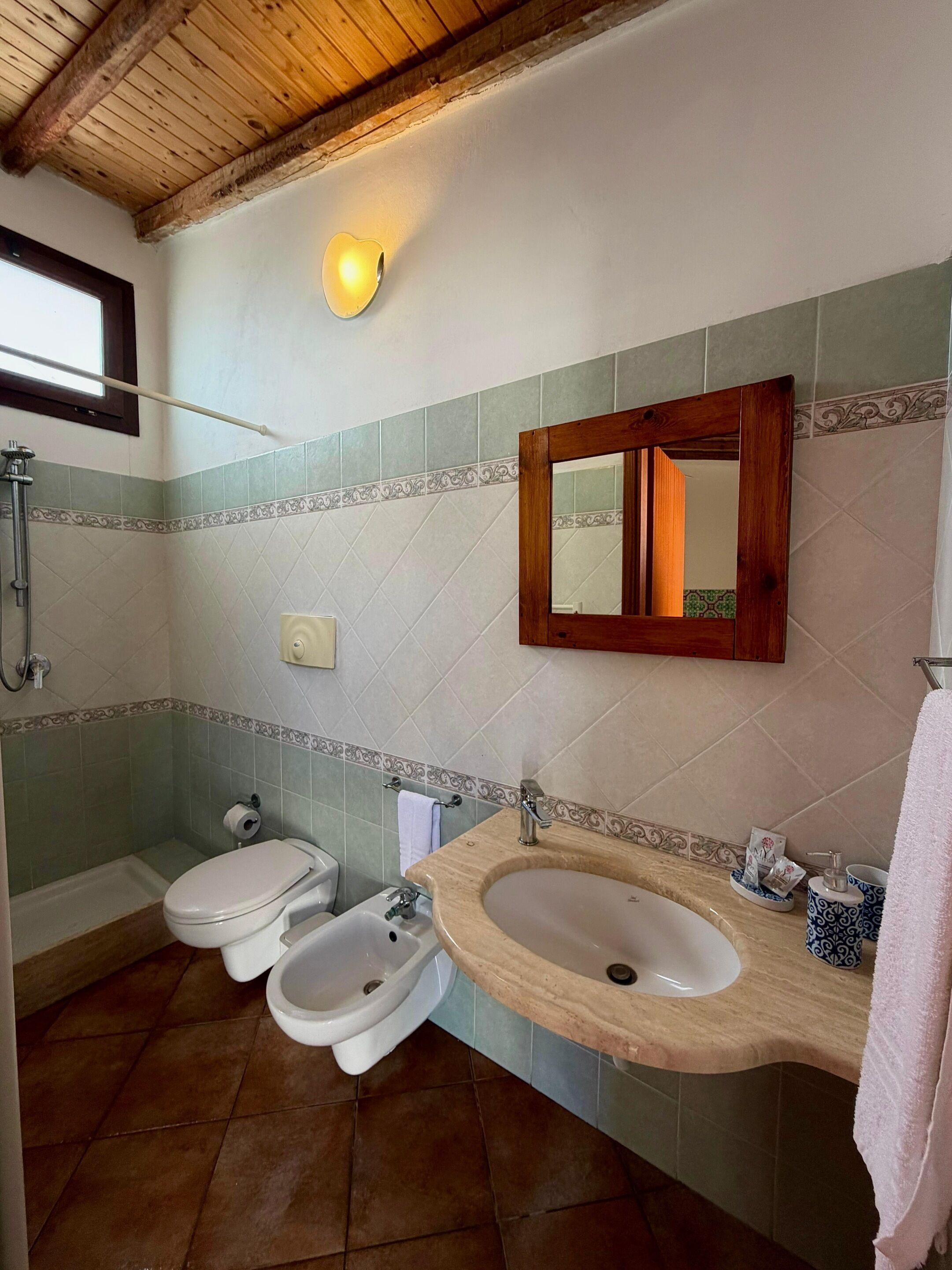 Ein Badezimmer mit Holzboden, einem großen Spiegel, einem Waschbecken und einer Dusche.