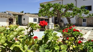 A courtyard with a pool, surrounded by buildings with white walls and tiled roofs. - Fattoria Manostalla (Partinico)