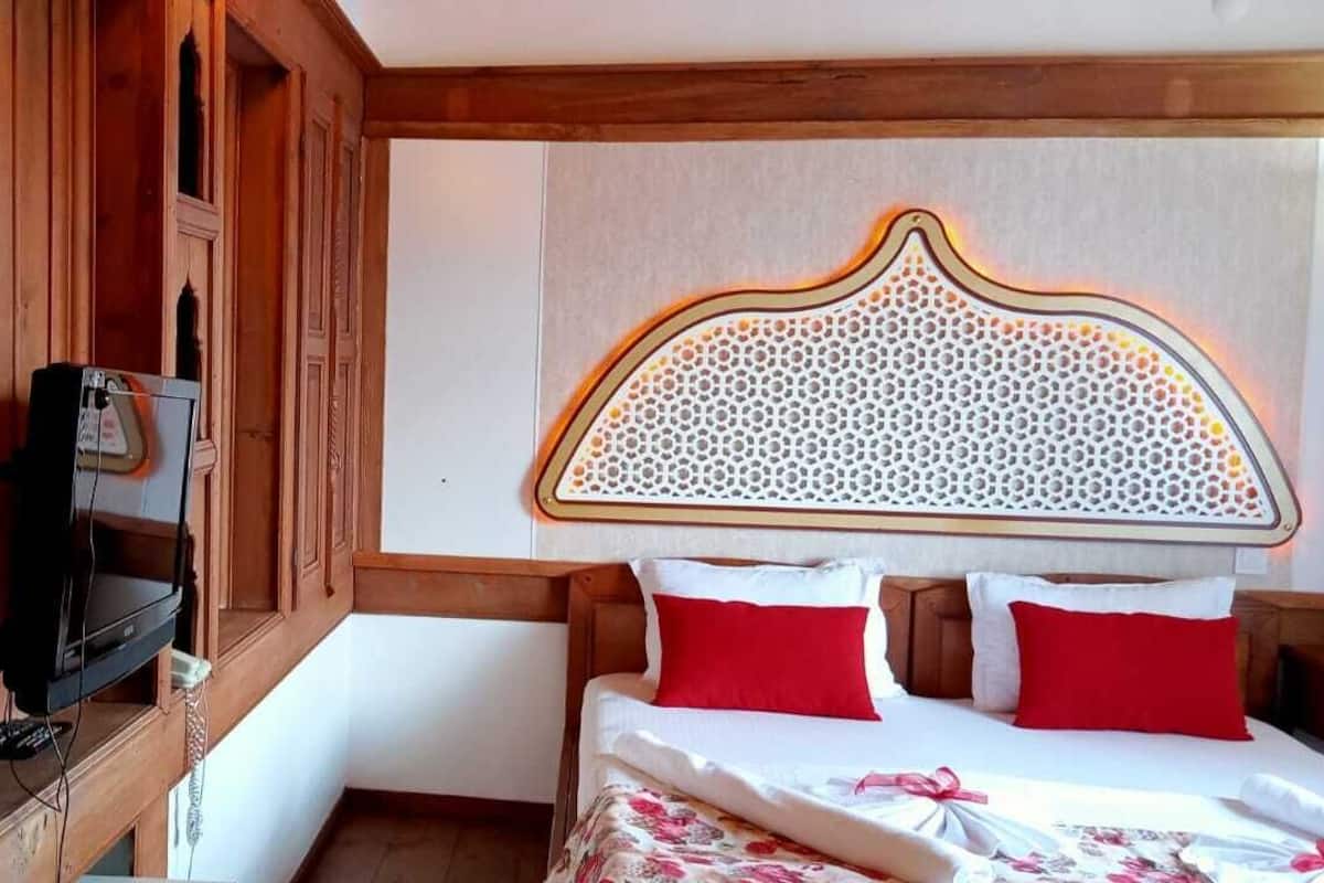 A hotel room with a bed, a television, and wooden cabinets.