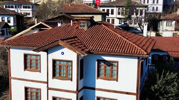 Un edificio de varios pisos con techo de tejas, un balcón y un pequeño espacio al aire libre con mesa y sillas.