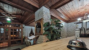 Un interior de madera con una recepción, una pared de piedra, un espejo grande y un ventilador de techo.