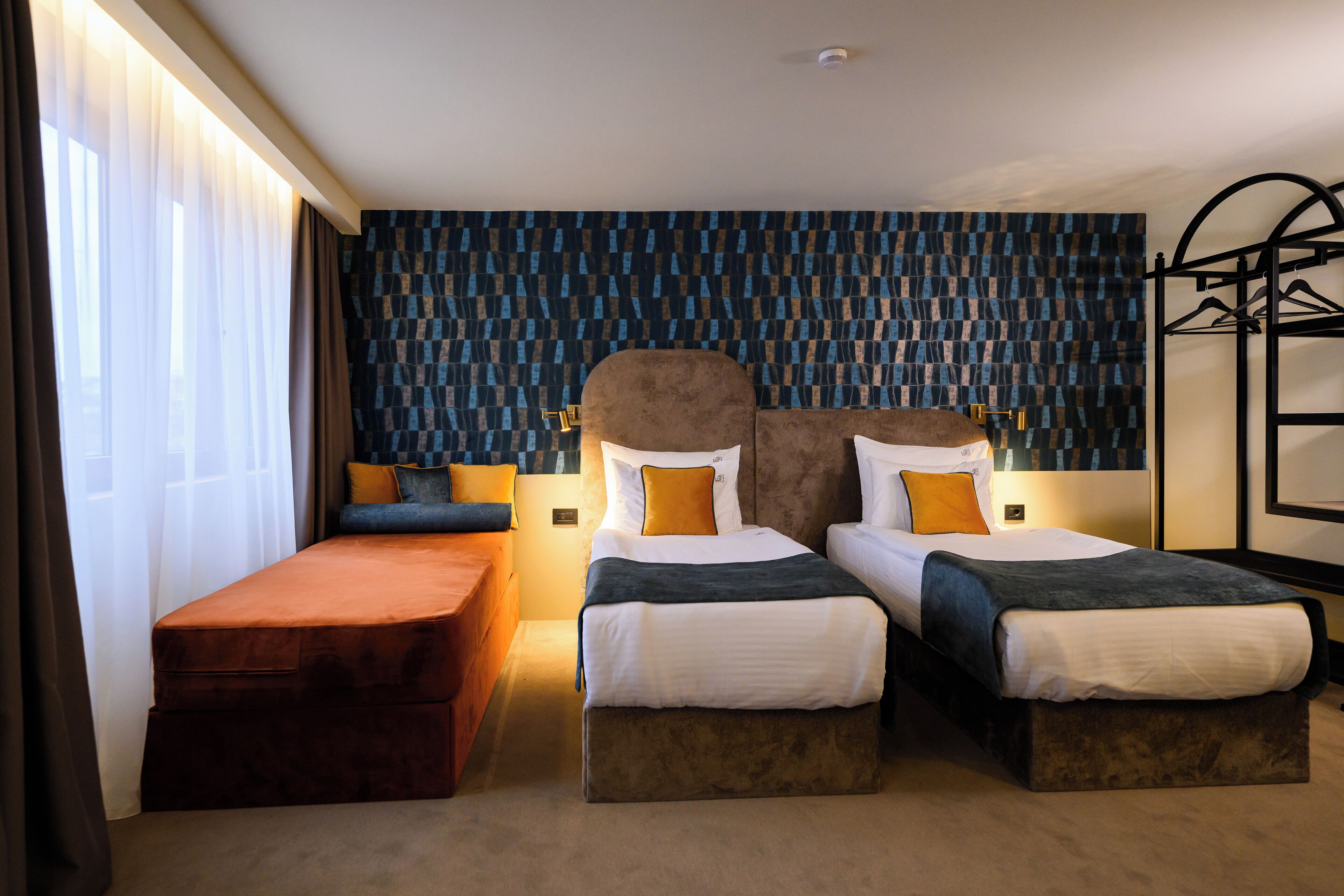 Habitación de hotel con dos camas, un banco y un armario.