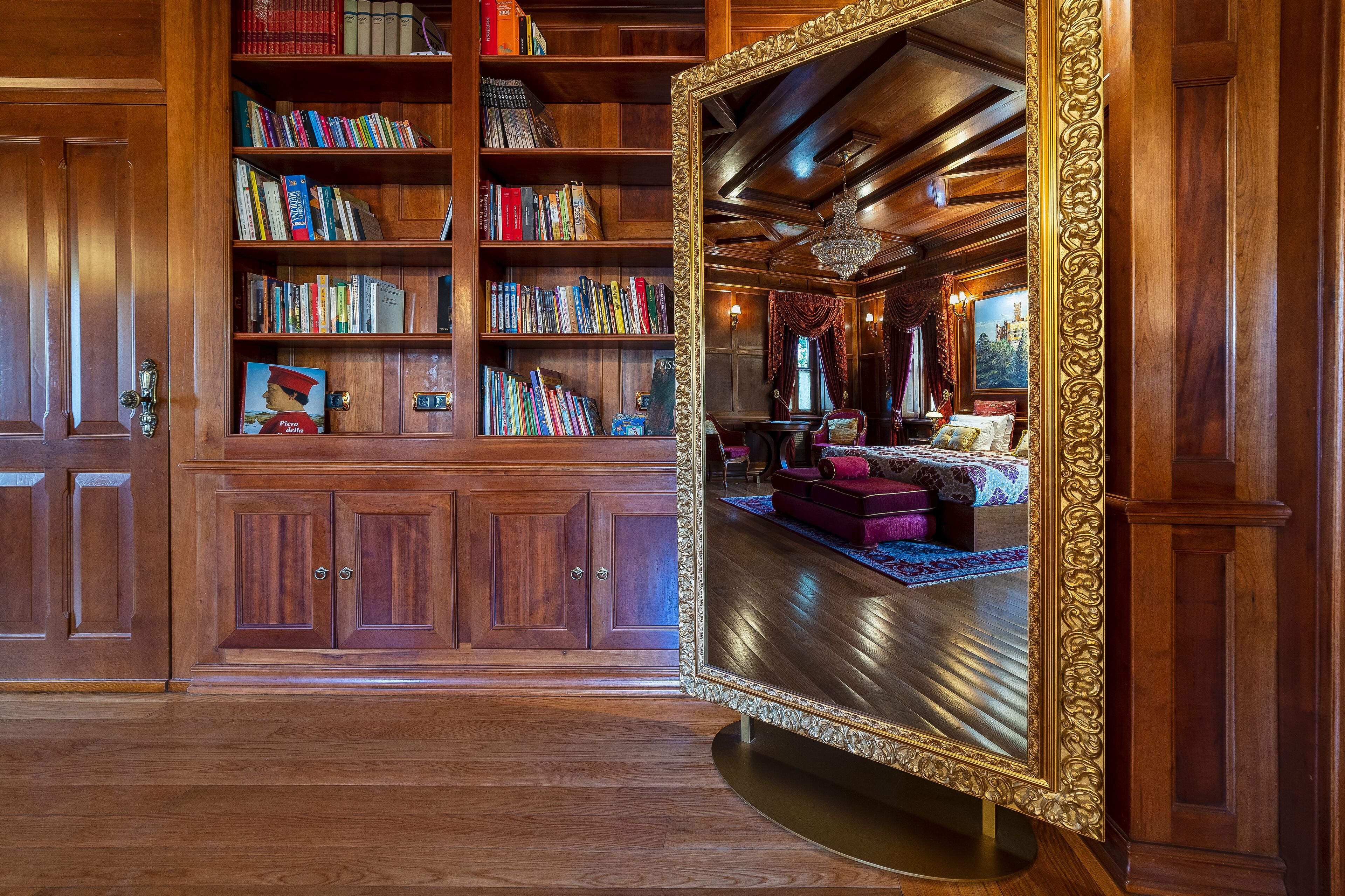 Una biblioteca con estanterías de madera y un espejo grande y decorado.